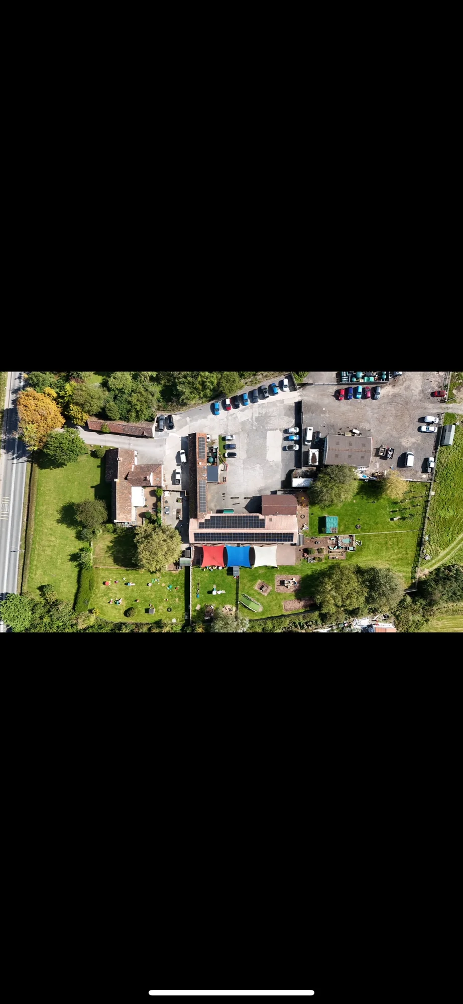 Aerial view of a stone cottage with a ground-mounted solar array